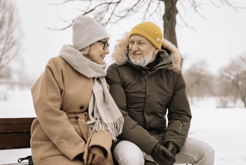 couple sat on bench, festive date in snow